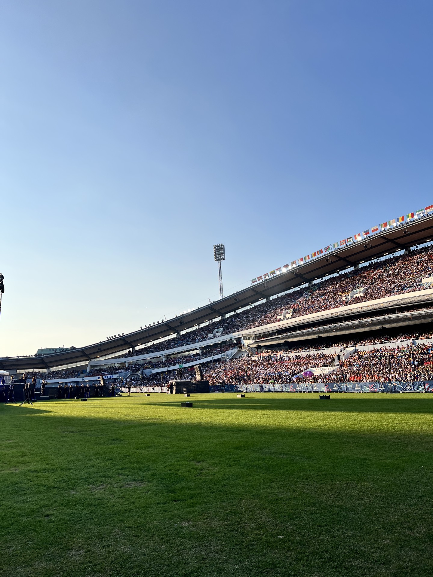 Football stadium with a green pitch, packed stands and international flags