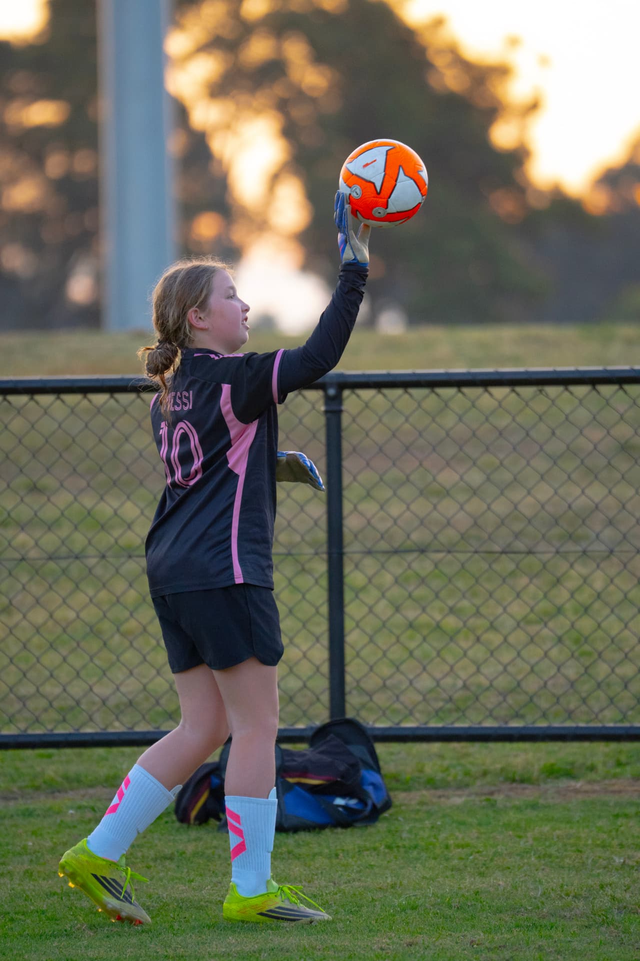 NextGen goalkeeper in a black and pink kit reaching up to catch a high ball