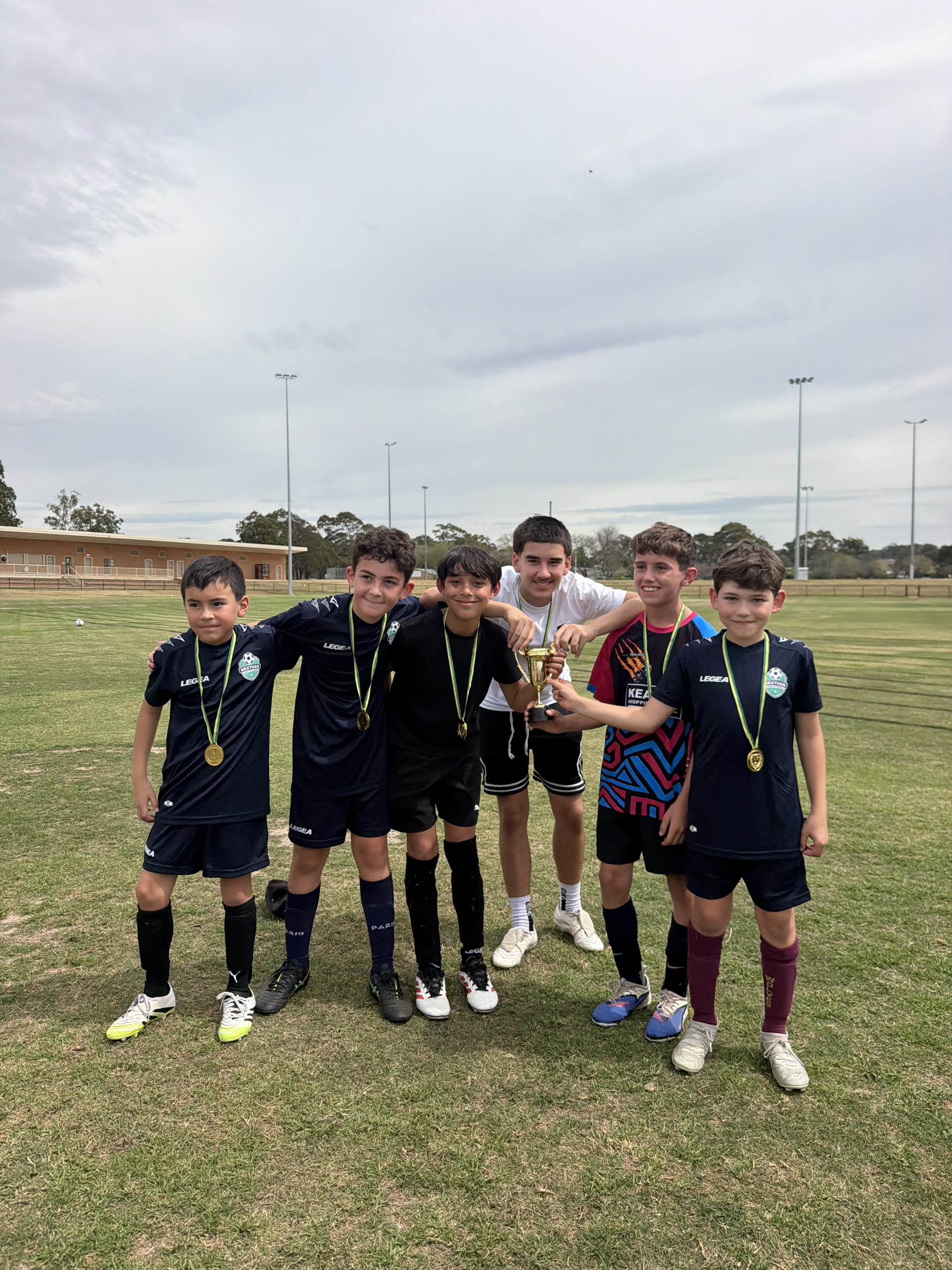 Six NextGen players posing together with a trophy and medals after a Mini World Cup day