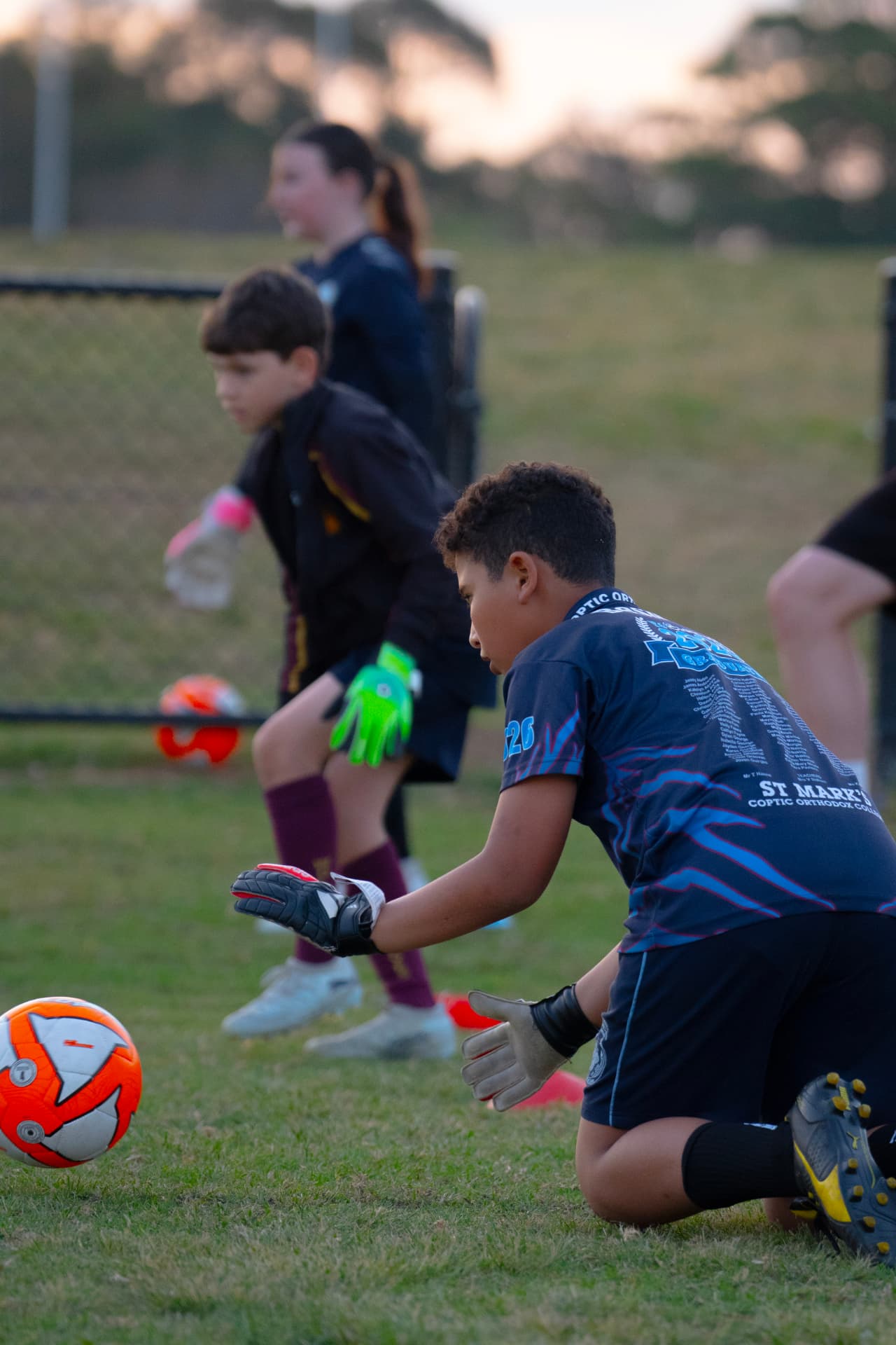 Line of NextGen goalkeepers practising low catches during a handling drill