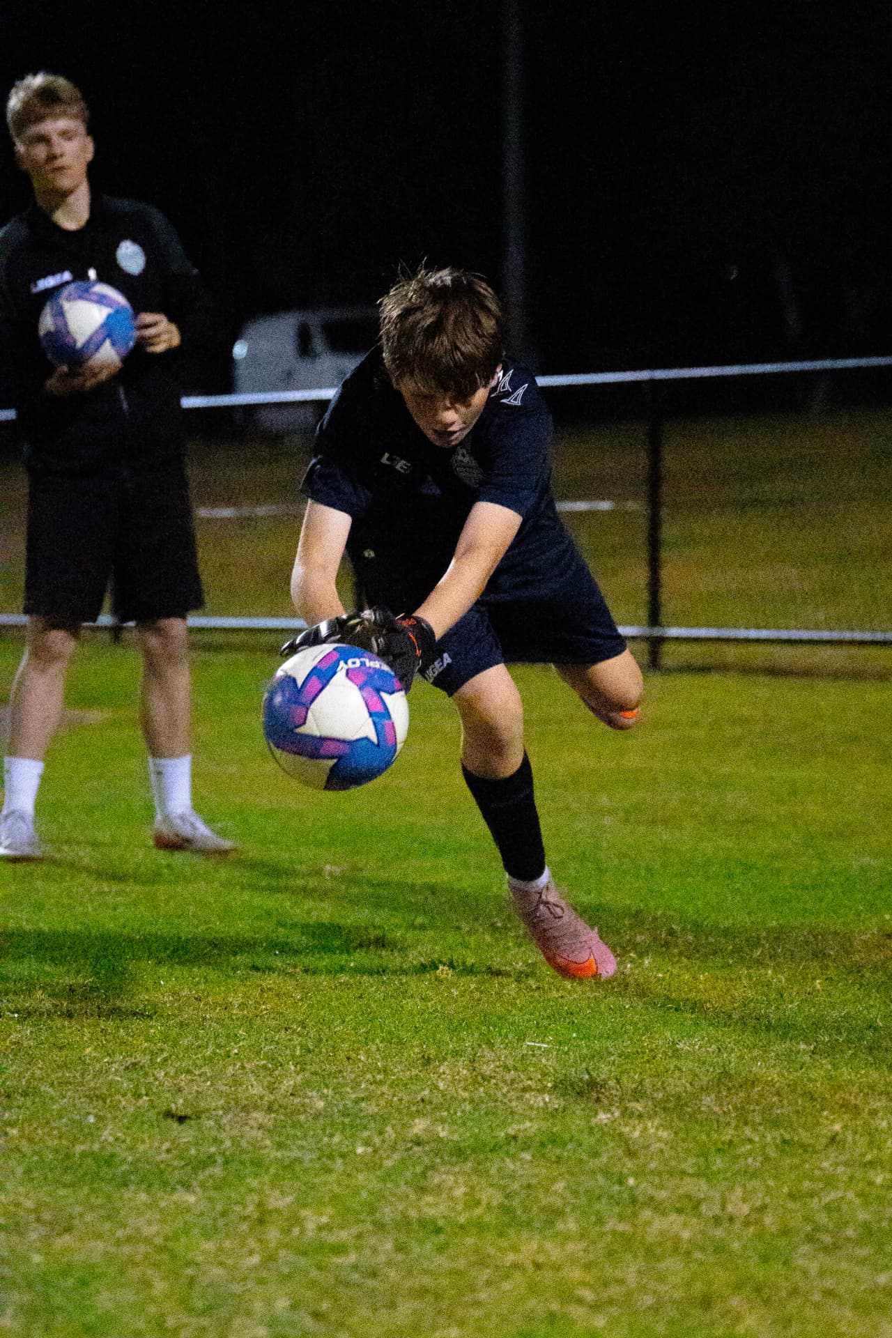 NextGen goalkeeper lunging to gather the ball during a handling drill