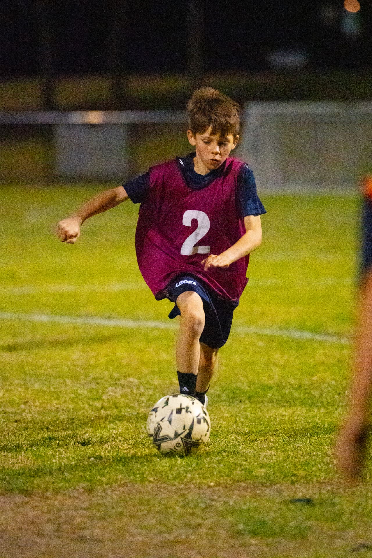 Young NextGen player in a purple bib practising dribbling