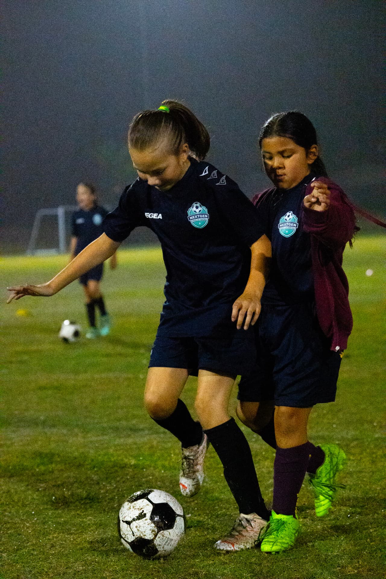 Two NextGen girls competing for possession during training