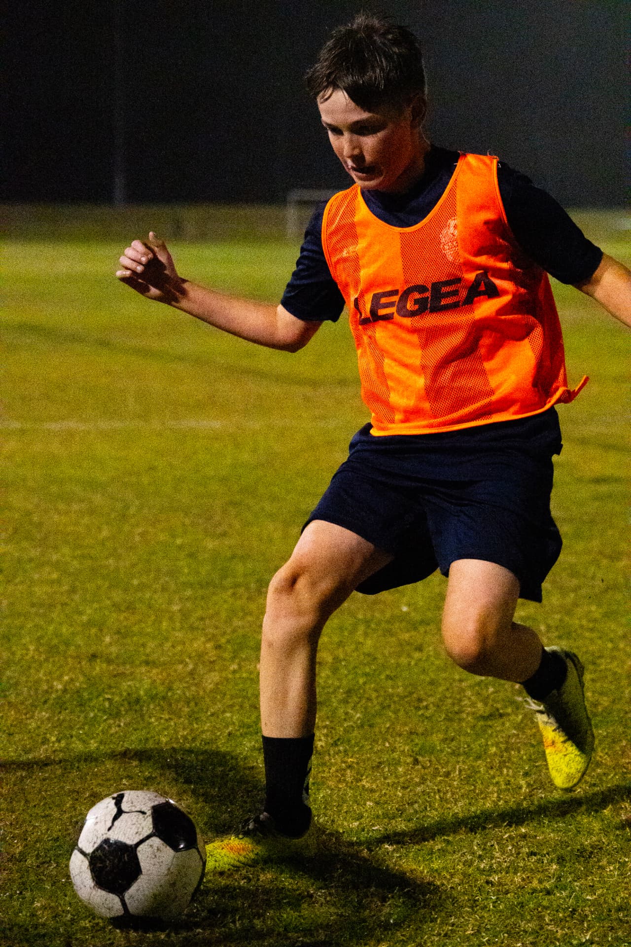NextGen player in an orange bib working with the ball
