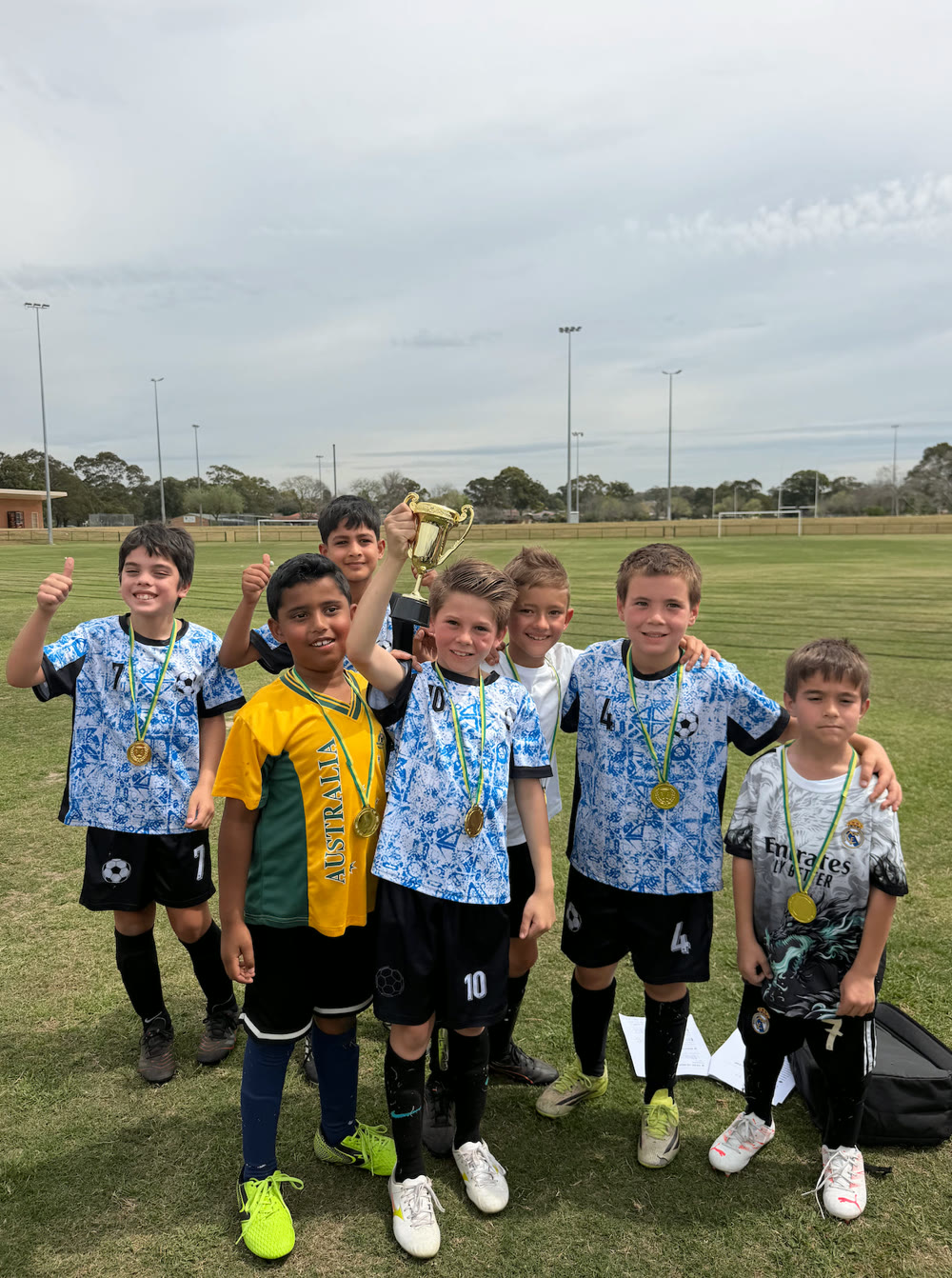 Seven NextGen players posing with a trophy and medals after a Mini World Cup day