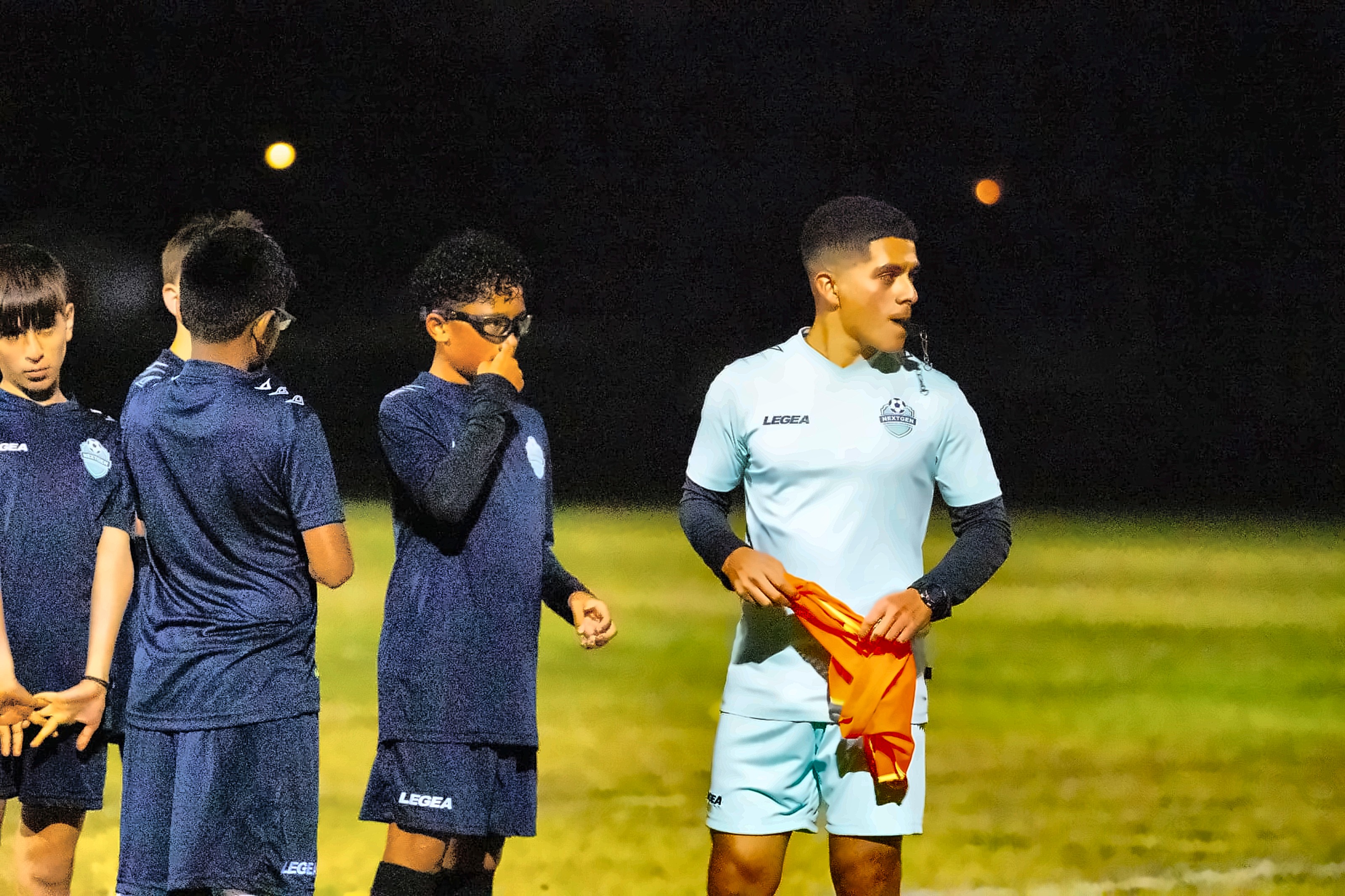 NextGen coach blowing the whistle during an evening training session